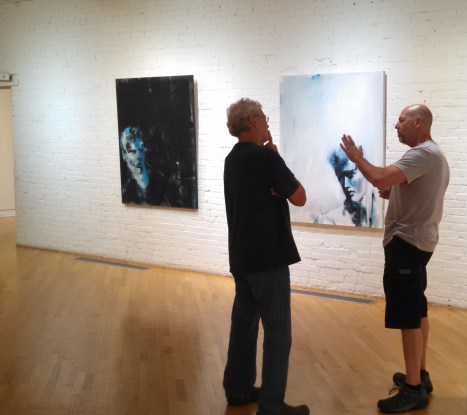 guys2gesturingwithartworkbehind